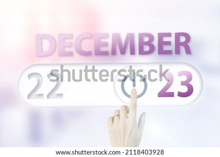 December 23rd. Day 23 of month, Calendar date.Hand finger switches pointing calendar date on sunlight office background. Winter month, day of the year concept