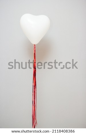 White balloon in the shape of a heart with a red garland, heart balloon for Valentine's Day