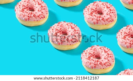 Creative pattern made of sweet pink cream  donuts on vibrant blue background.  Bold colors. Diagonal copy space.