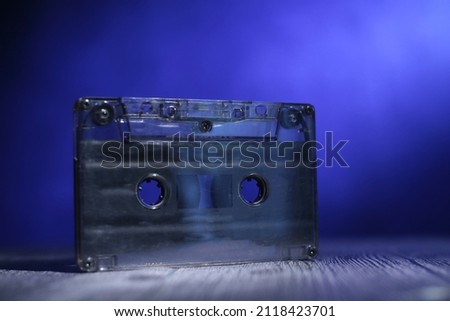 Retro cassette tape under light, against blue background