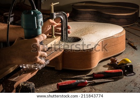 Luthier cutting a channel to place the truss rod in the guitar neck Royalty-Free Stock Photo #211843774