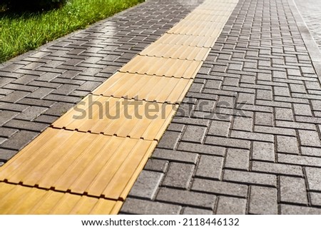 Tactile paving on pedestrian walkway, yellow tactile tiles outdoor. Tactile ground surface indicators for blind and visually impaired. Detectable warnings outside