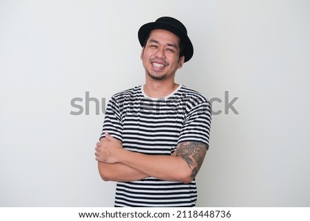 Tattooed Asian man smiling happy with arms crossed