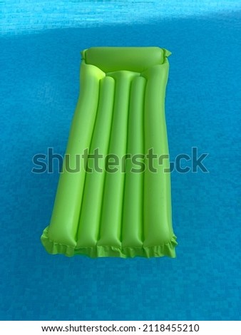 green air mattress is floating in blue water of a swimming pool. from above
