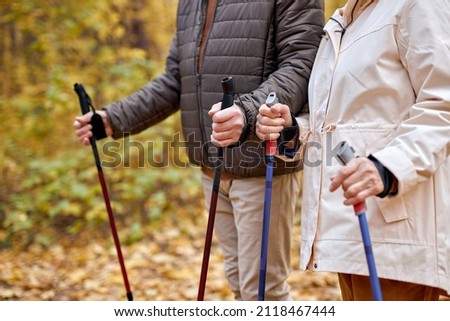 senior elderly grandmother grandfather training Nordic walking with ski trekking poles in forest. Old man woman tourists hiking with sticks in forest. Active rest outdoors of mature couple
