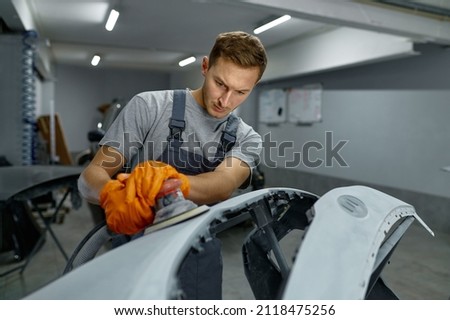Repairman with sander removing old paint car Royalty-Free Stock Photo #2118475256