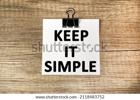 Be more simple. Motivational inspirational text on white paper on a wooden background.