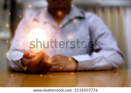 Businessman hand holding lightbulb with orange glowing and connection line. Creative thinking idea concept.Minister of innovation and innovative technology