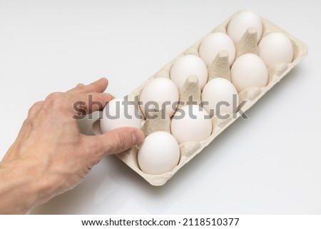 a man's hand takes out a white egg from a cell. High quality photo