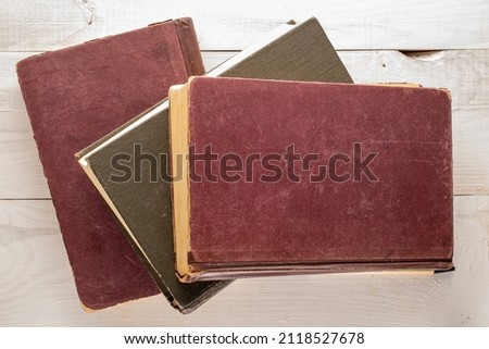 Three old books on a wooden table, macro shot, top view.