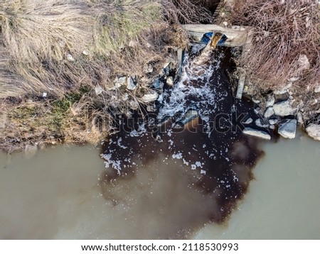 Hazardous chemicals are released into the river. Industrial waste water, aerial done view. Sewage drains into the river. Environmental pollution. Ecological catastrophe and disaster. Contamination. Royalty-Free Stock Photo #2118530993