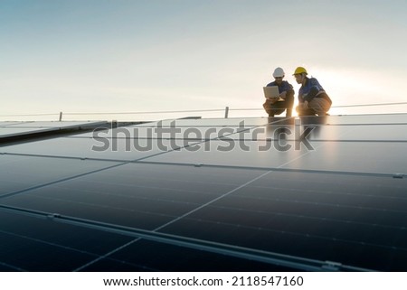 Specialist technician professional engineer with laptop and tablet maintenance checking installing solar roof panel on the factory rooftop under sunlight. Engineers team survey check solar panel roof. Royalty-Free Stock Photo #2118547160
