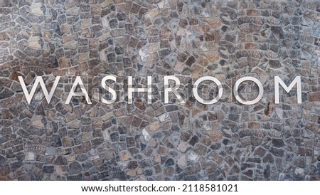 Washroom metal sign text letters on stone wall rough background