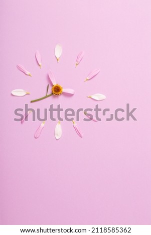 abstract clock made of flower petals on  pink background
