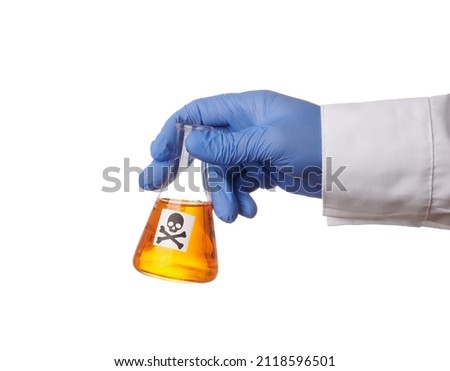 Doctor hand holds retort with toxic orange liquid - isolated photo on a white background. Death symbol on a glass container. Chemical flask with yellow poison in a scientist hand. Blue nitrile glove Royalty-Free Stock Photo #2118596501