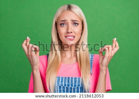 Photo of scared frightened anxious lady bite lip crossed fingers wear striped overall isolated green color background