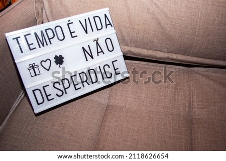 decorative plate with the phrase "time is life don't waste" in portuguese on a sofa