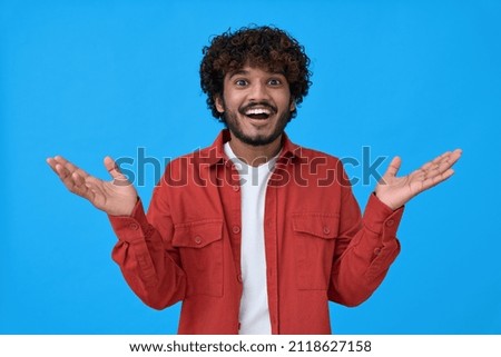 Surprised excited young indian man looking at camera with wow face expression feeling amazed advertising shopping promotion, great betting win standing isolated on blue background.