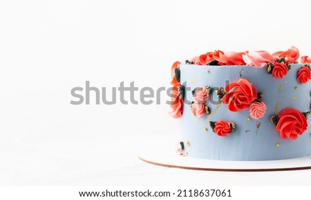 Birthday cake with blue cream cheese frosting decorated with red flowers on the white background