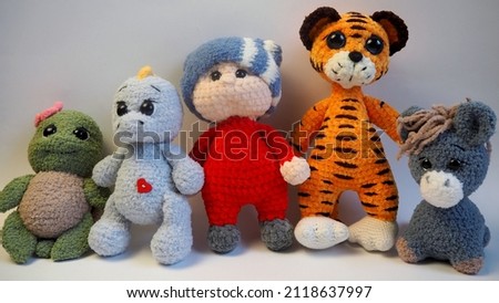 knitted toys turtle, donkey, tiger, boy, child, dinosaur, elephant stand on a gray background. side view