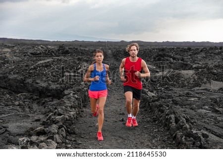 Athletes couple running runners exercising endurance in volcanic landscape extreme terrain. Man runner, Asian woman jogging in activewear sportswear. Fitness exercise workout training for triathlon. Royalty-Free Stock Photo #2118645530