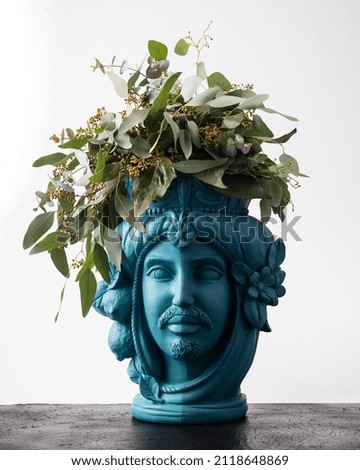 decorative vase depicting a man's head with plants and flowers.