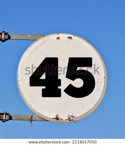 A round white sign, showing a black coloured number forty five (number 45) 