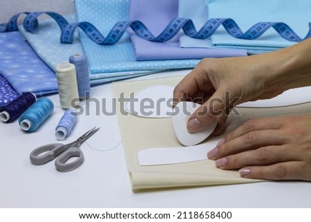 Rabbit pattern, we cut out the toy with our hands. Sew a plush bunny. Hand sewing process with cloth, scissors, sewing accessories. Royalty-Free Stock Photo #2118658400