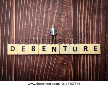 Top view miniature people and toys word with text DEBENTURE on wooden background.