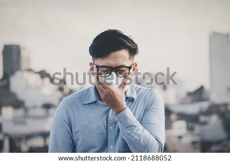 Man wearing N95 PM 2.5 the respiratory protection mask against air pollution and dust particles exceed the safety limits. Healthcare, environmental, ecology concept. Allergy, headache. Royalty-Free Stock Photo #2118688052