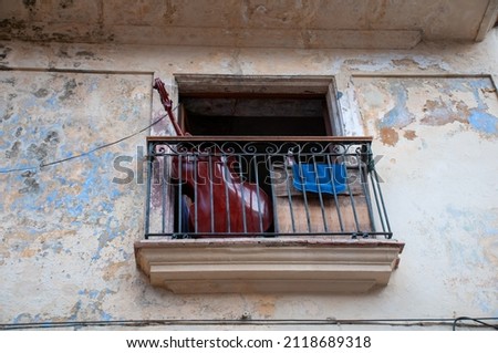 Cello on a balcony with faded and aged facade of old Havana. Cuba.