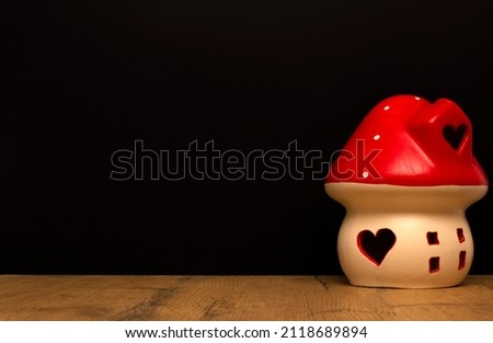 Mushroom-shaped house with hearts on a black background. Love valentine concept