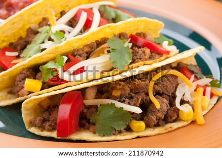 Assorted Mexican dishes, with whole grain corn beef tacos as the main subject. 