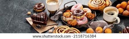 Table with various cookies, donuts, cakes and coffe cups on dark backround. Panorama, banner Royalty-Free Stock Photo #2118716384