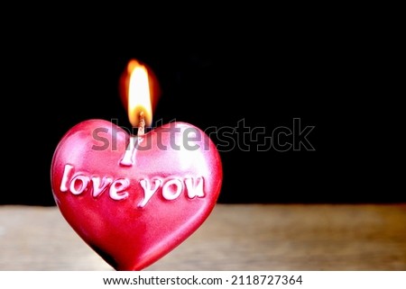 Close up view of red burning candle in the shape of heart on dark background. valentine day and I love you concept