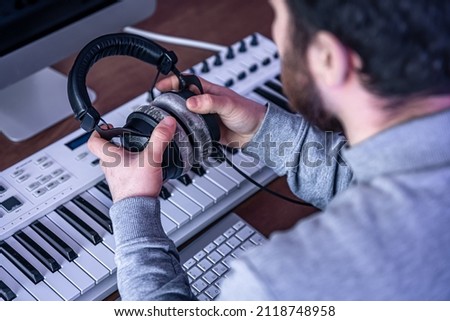 Male musician creates music using computer and keyboard, musician workplace.