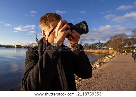 Photographer taking a picture with a dslr during sunny autumn day at park.