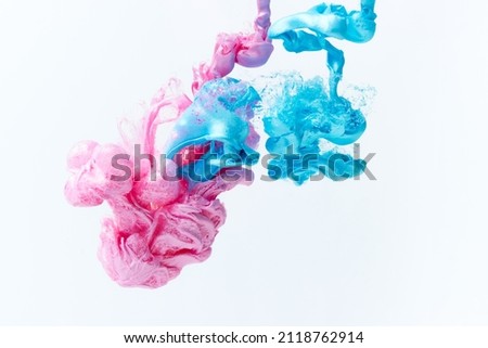 Pink and blue paints splash curves in water on white. Acrylic paint drop background. Abstract colors swirl texture