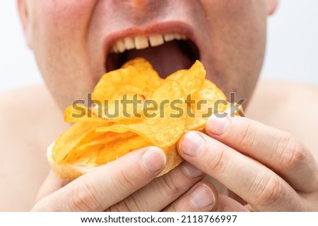Overeating junk food, Slice of toasted bread with butter and lots of chips, Holding a fat belly, Concept, Obesity, Excessive consumption of saturated fat 