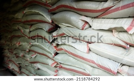 hundreds of stacks of rice sacks with a volume of twenty-five kilo grams, which are stored in the storage room of a warehouse for long-term food reserves.