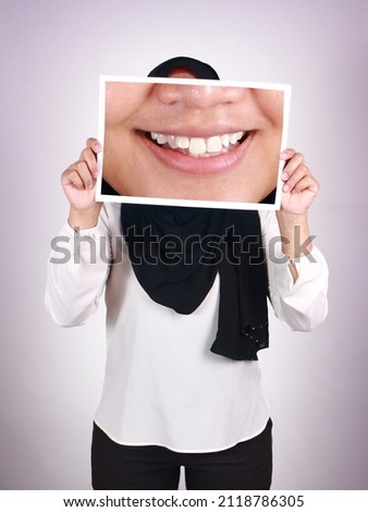 Anonymous muslim woman wearing hijab covering her face with big smile picture, happy white teeth concept