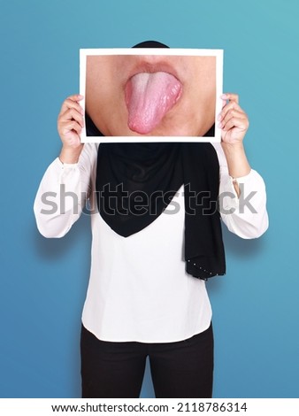 Anonymous muslim woman wearing hijab covering her face with sticking tongue out picture, mocking gesture concept
