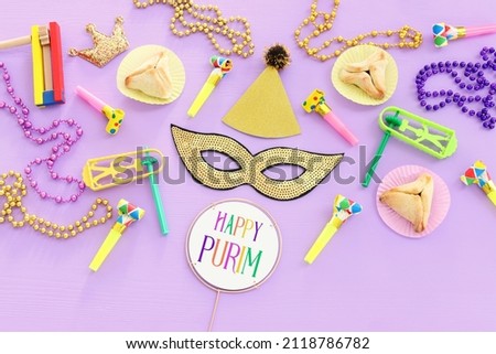 Purim celebration concept (jewish carnival holiday) over wooden purple background. Top view, flat lay