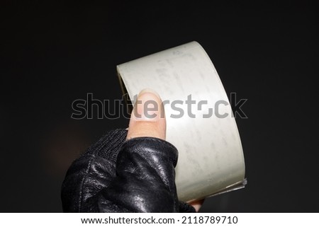 Reel of scotch tape in hand on dark background close up