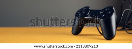 black game controller isolated on yellow table background