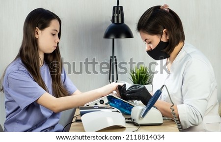 Hardware manicure in the salon. The master makes a manicure to a girl in a beauty salon. The concept of professional nail care. Royalty-Free Stock Photo #2118814034