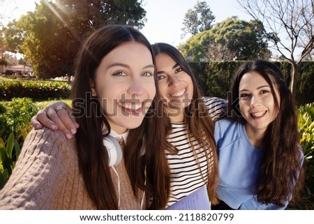 Three happy female students taking a picture of each other. Real life friends moment. Three students having fun together on college campus taking a photo.
