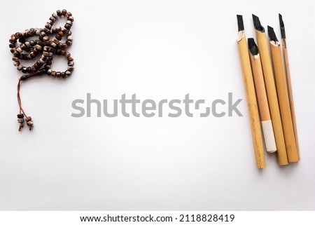 Blank sheet of paper with traditional Arabic kalams for calligraphy and prayer beads