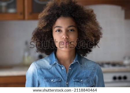 Pretty beautiful African American teen girl with Afro hairstyle looking at camera, posing for shooting at home. Black teenage high school student, teenage schoolgirl head shot portrait