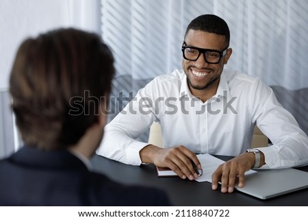 Happy African intern meeting with mentor, company coach, listening to teacher, smiling, laugh. Job seeker meeting business owner for interview. Manager, banker giving consultation to client Royalty-Free Stock Photo #2118840722
